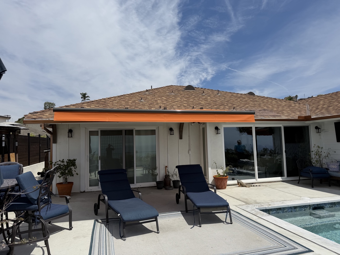 Bold orange cassette retractable awning extended over a poolside patio
