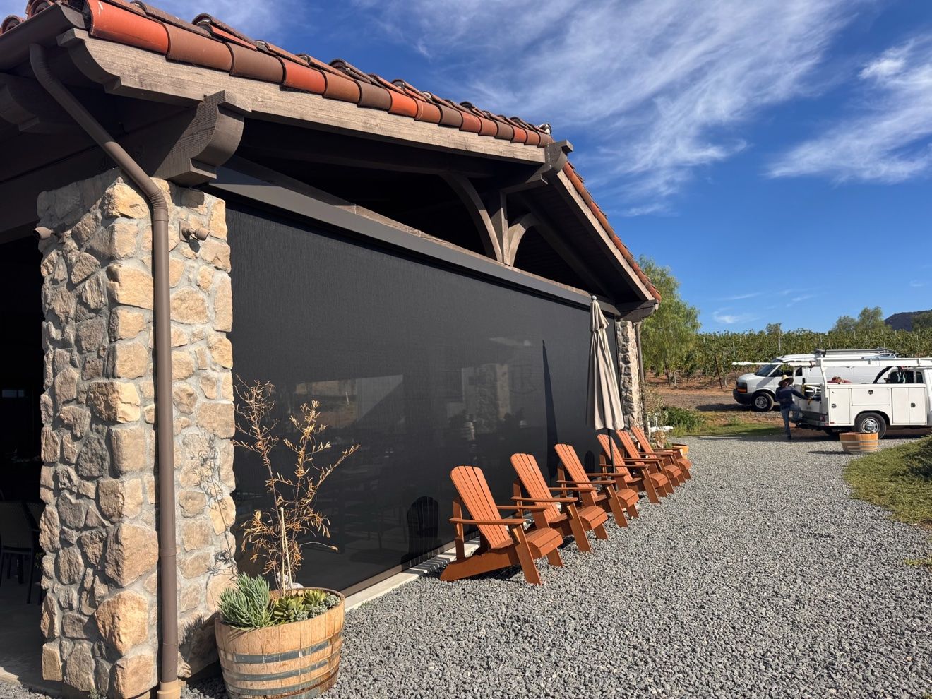 Motorized power screens installed on a stone winery building patio, AJ Shades commercial shade project