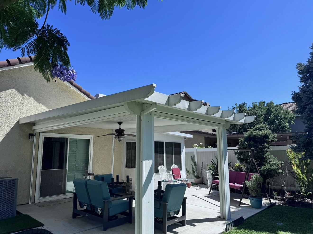 White solid aluminum patio cover with ceiling fan over a furnished backyard patio